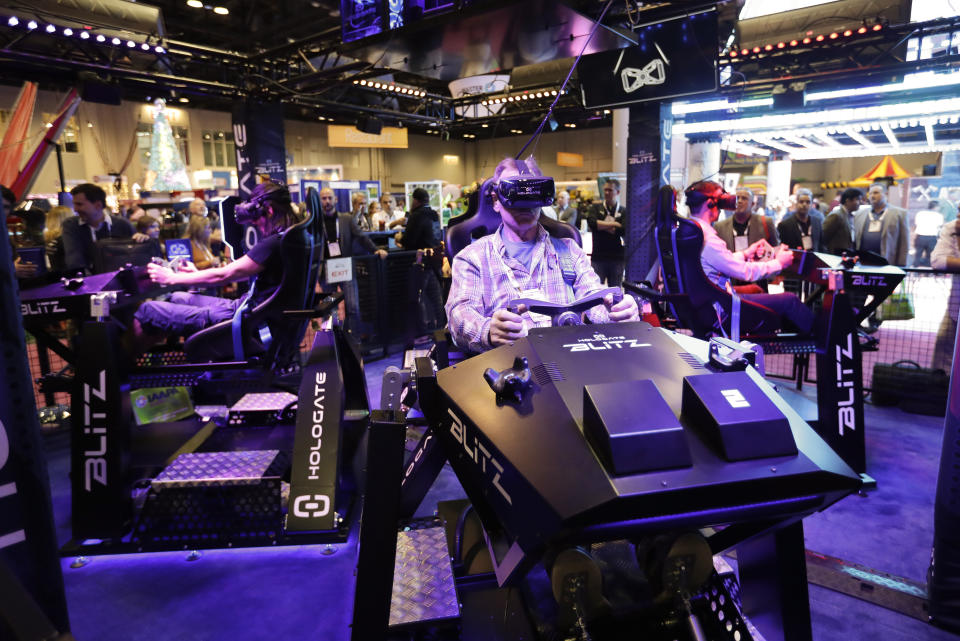 Attendees sample one of the many virtual reality rides during the International Association of Amusement Parks and Attractions convention Tuesday, Nov. 19, 2019, in Orlando, Fla. (AP Photo/John Raoux)