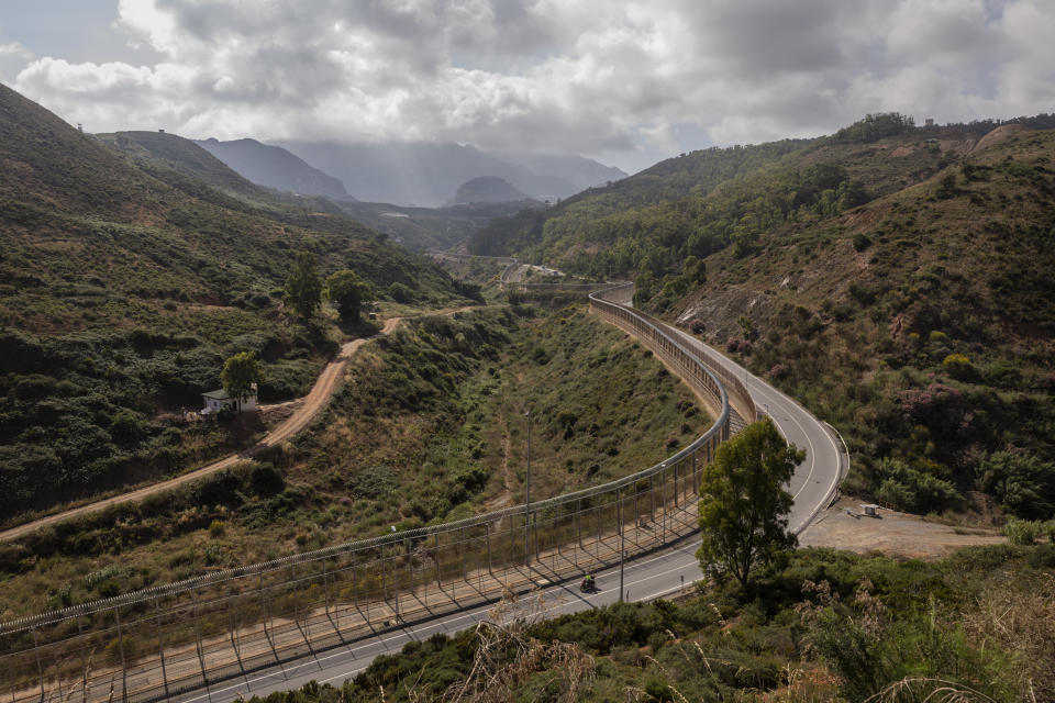 FILE - A motorcycle rides on the Spanish side of the border fence that separates Spain and Morocco in the Spanish enclave of Ceuta, June 3, 2021. Russia’s invasion of Ukraine is certain to dominate an upcoming NATO summit in Madrid. But host nation Spain and other members are quietly pushing the Western alliance to consider how mercenaries aligned with Russian President Vladimir Putin are spreading Moscow’s influence in Africa. (AP Photo/Bernat Armangue, File)