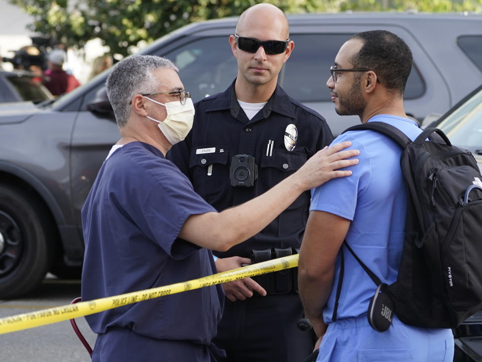 Hospital staff talk to a Los Angeles Police officer after a suspect who stabbed multiple people remained barricaded inside the Encino Hospital Medical Center in Encino, Calif., Friday, June 3, 2022. After a standoff, the suspect was taken into custody and into an ambulance. (AP Photo/Damian Dovarganes)