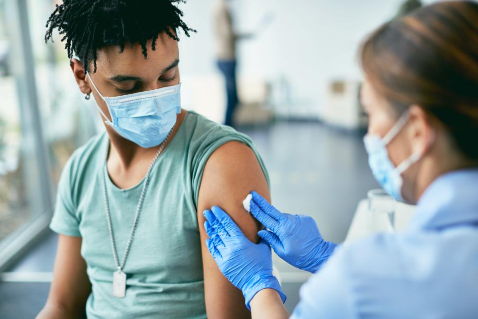 Une jeune personne portant un masque reçoit un vaccin