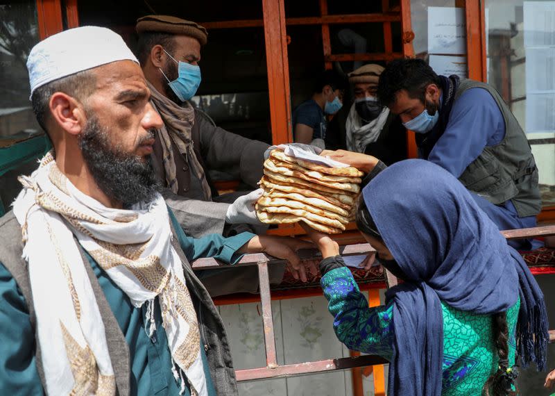 An Afghan girl receives free bread distributed by the government, outside a bakery, during the coronavirus disease (COVID-19) outbreak in Kabul