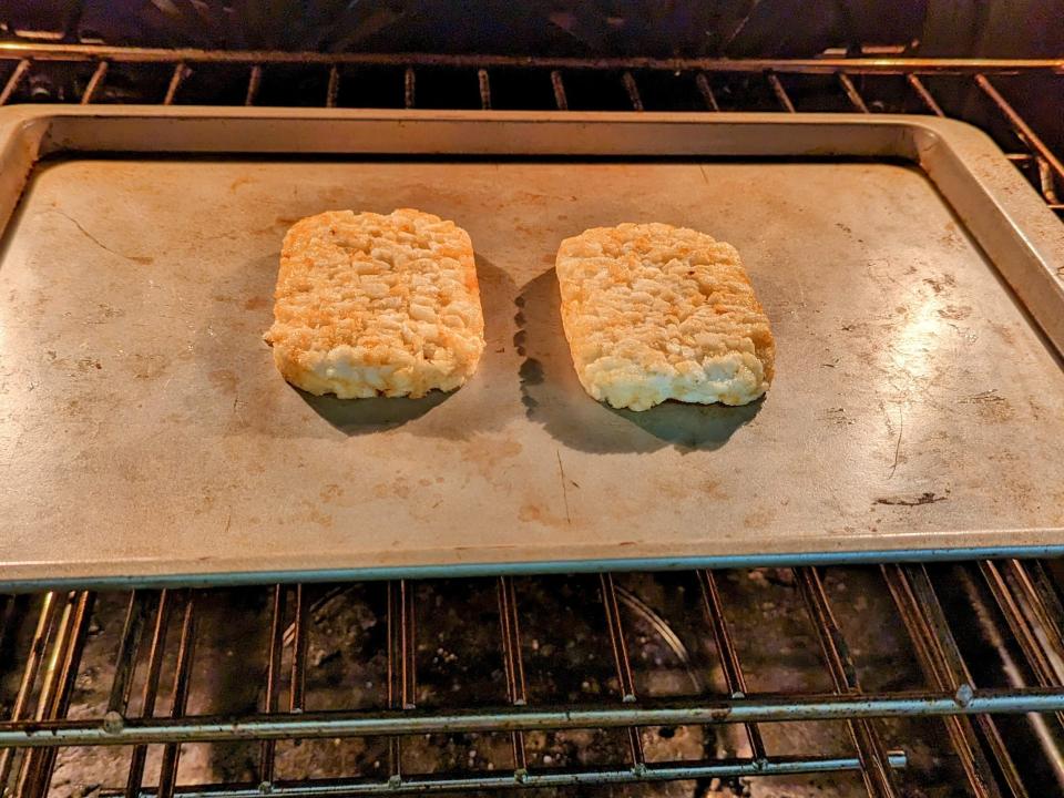 two hash brown patties on a cooking sheet in the oven