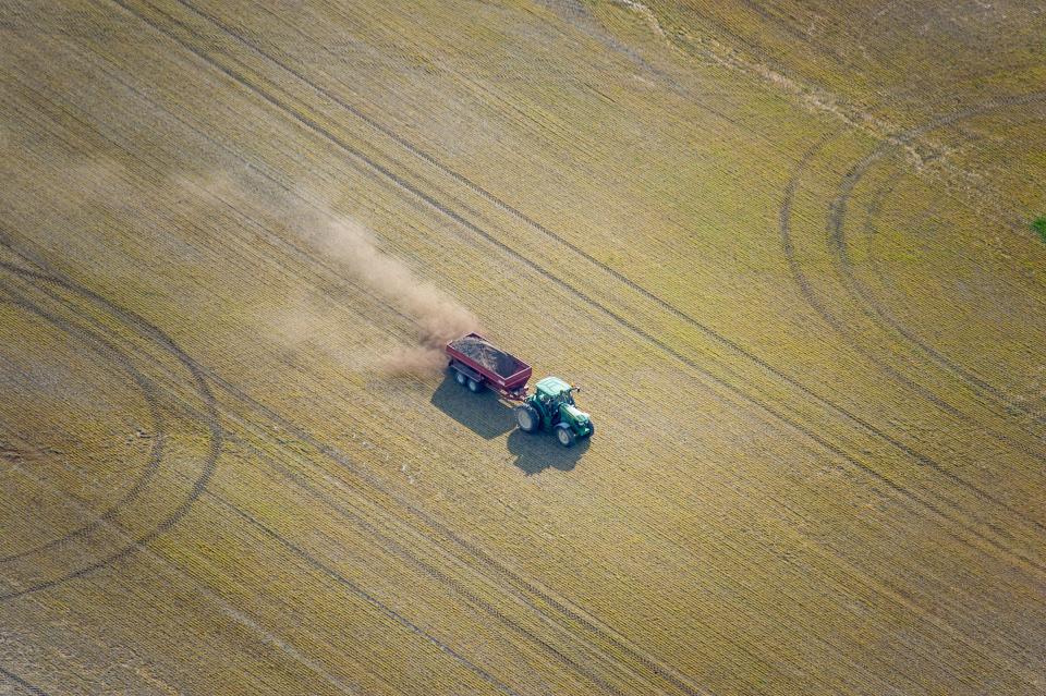 Farmer spreading chicken manure on crop field as fertilizer on the eastern shore of Maryland, USA.