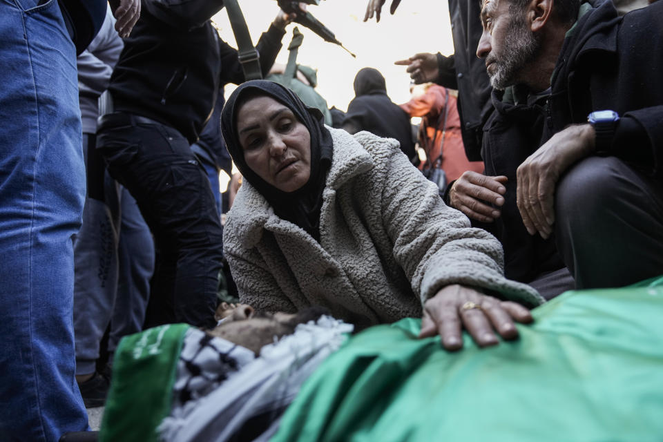 Mourners react over the bodies of six Palestinians, draped in the Hamas flags during their funeral in the West Bank city of Jenin on Sunday, Jan. 7, 2024. Six Palestinians and a member of Israel's paramilitary border police were killed in confrontations in a hot spot of violence in the Israeli-occupied West Bank, the Palestinian Health Ministry and the Israeli military said Sunday. (AP Photo/Majdi Mohammed)