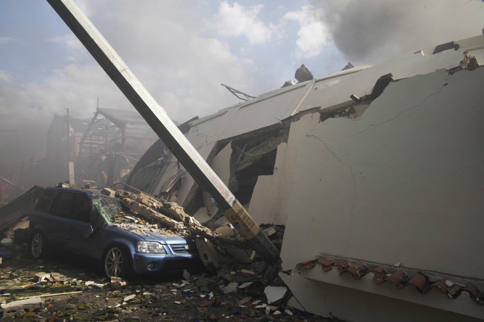 A car is covered in debris next to a collapsed building, both damaged in an explosion at the Polyplas plant in the Villas Agricolas neighborhood in Santo Domingo, Dominican Republic, Wednesday, Dec. 5, 2018. The mayor told reporters the fire began when a boiler exploded early Wednesday afternoon at the plastics company. Authorities say at least two people have died. (AP Photo/Tatiana Fernandez)