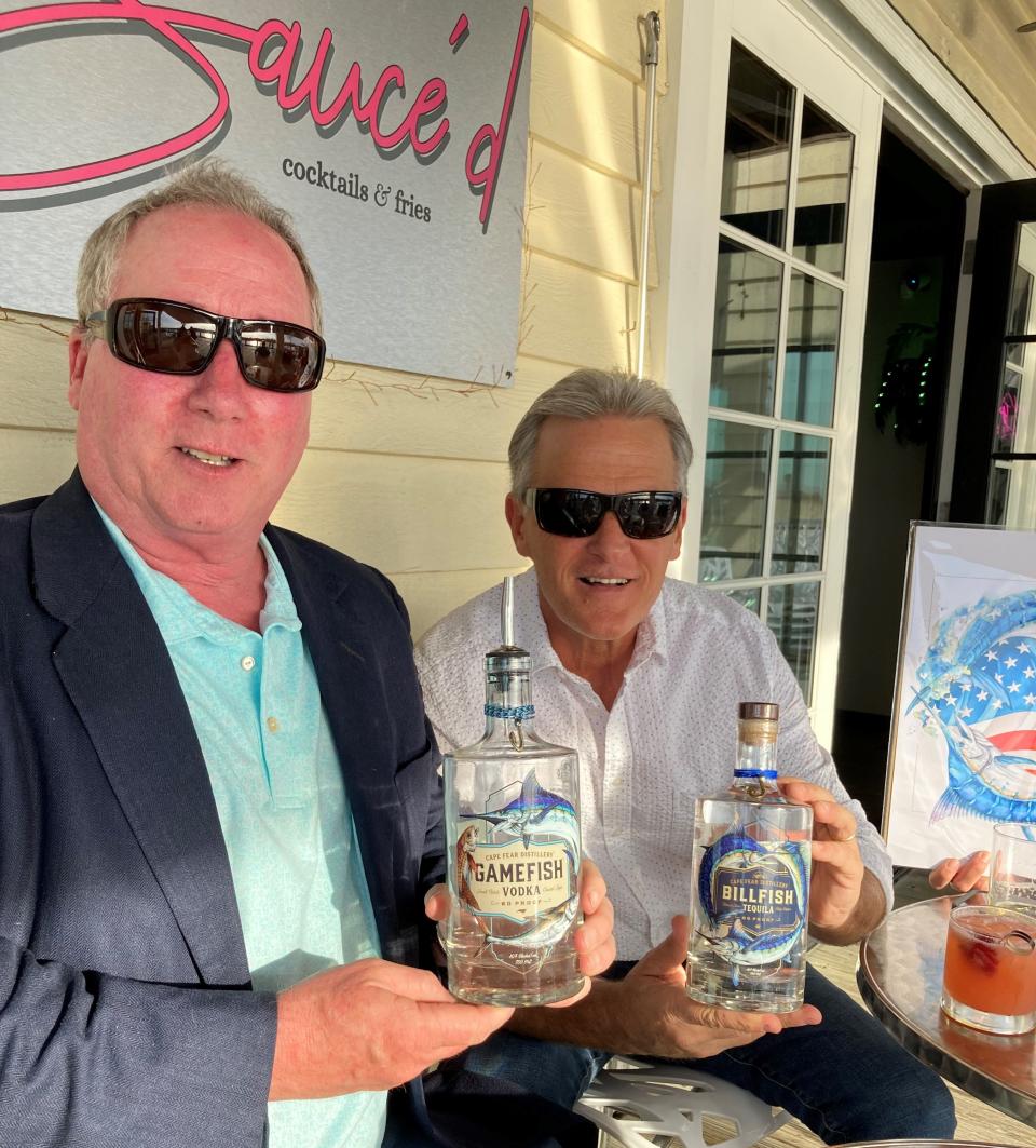 Alex Munroe (left) and artist Steve Goione (right), with two of the spirits from Cape Fear Distillery. ALLISON BALLARD/STARNEWS
