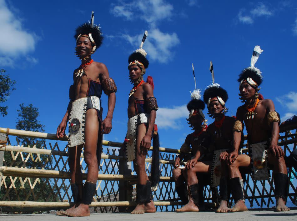 Naga tribesmen from the Yimchunger tribe gesture as they rest of their Morung on the first day of the state annual Hornbill Festival. Morungs are large youth dormitories constructed at the head of villages, often to guard them but fundamentally for providing an educational foundation in social and cultural values. Boys and girls are admitted into the their respective Morungs upon reaching puberty. Today, the Morung system is endangered as more and more Nagas have moved away from it.