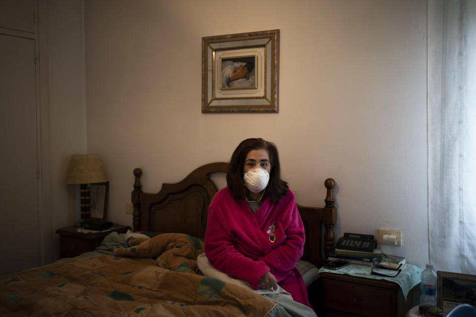 In this April 28, 2020 photo, Mercedes Pascual, an assistant nurse poses for a photo in her home as she recovers after being tested positive for the new coronavirus in Duruelo de la Sierra, Spain, in the province of Soria. Pascual, who works in the local nursing home, has spent over 45 days isolated in her room and says she can't wait to go back to work and help her overburdened colleagues. Many in Spain's small and shrinking villages thought their low populations would protect them from the coronavirus pandemic. The opposite appears to have proved true. Soria, a north-central province that's one of the least densely peopled places in Europe, has recorded a shocking death rate. Provincial authorities calculate that at least 500 people have died since the start of the outbreak in April. (AP Photo/Felipe Dana)