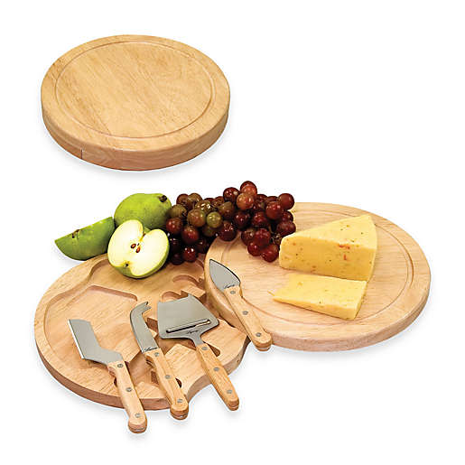 Round wooden cheese board and slicing tools topped with grapes and cheese