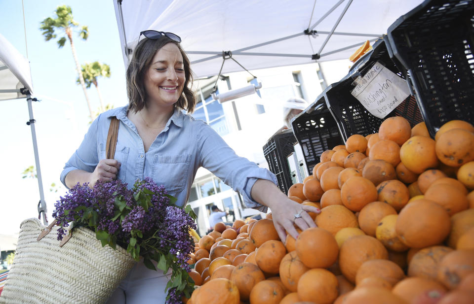 This April 10, 2019 photo shows Gaby Dalkin shopping for oranges at Santa Monica Downtown Farmers Market in Santa Monica, Calif. Dalkin, the chef behind the popular Website and social media accounts, "What’s Gaby Cooking," is forging her own path. Every Monday she posts a live demo to Instagram as she cooks dinner which has become appointment viewing for some fans. Her husband films it and reads questions from viewers as she’s cooking. (AP Photo/Chris Pizzello)