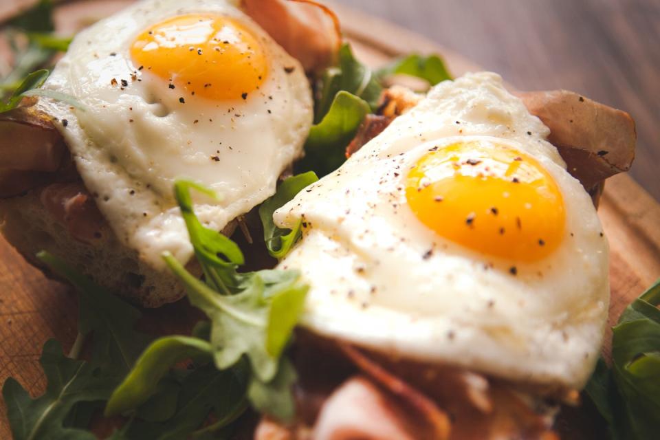 fried eggs sunny side up on baguette, ham and arugula