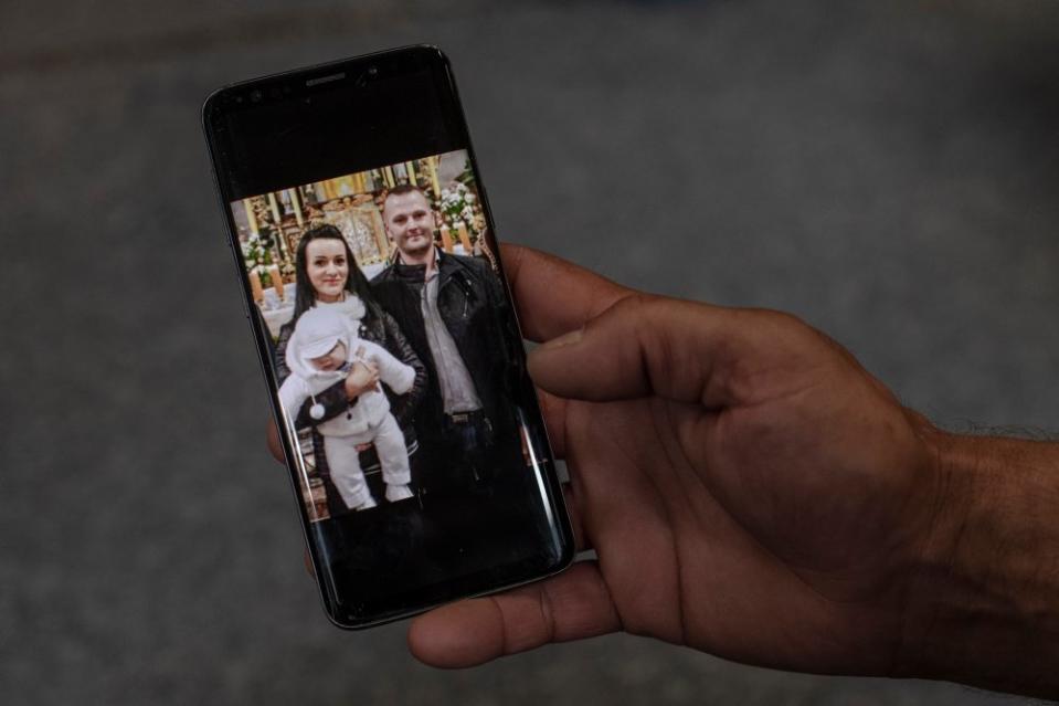 Janusz Kucharski shows a photo of Justyna and himself from the baptism of their son, Dawid.<span class="copyright">Kasia Strek for TIME</span>