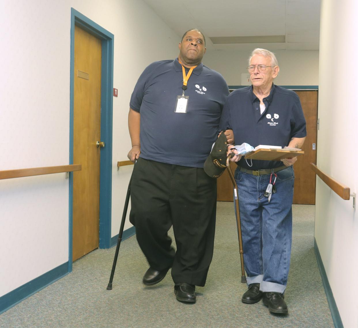 Akron Blind Center member Brian Banks, left, gets a hand maneuvering the hallway from Tom Pavlik on Thursday, Dec. 22, 2022, in Akron.