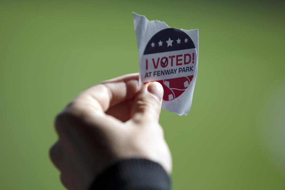 A voter holds a sticker after casting a ballot at Fenway Park, Saturday, Oct. 17, 2020, in Boston. (AP Photo/Michael Dwyer)