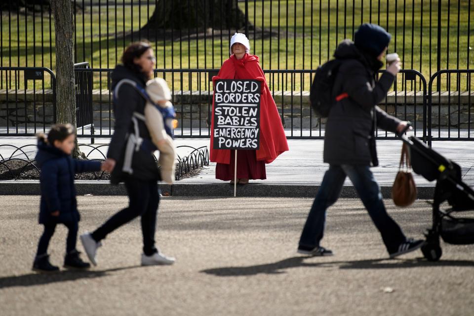 People walk past an activist dressed as a character from the TV show The Handmaid's Tale during a protest against US President Donald Trump immigration policy near the White House Feb. 18, 2019 in Washington, DC.  (Photo: Brendan Smialowski/AFP/Getty Images)