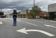 An Alabama state trooper checks his phone as investigators work at the site of a fatal shooting in downtown Dadeville, Ala., on Sunday, April 16, 2023. Several were killed during a shooting at a birthday party Saturday night, the Alabama Law Enforcement Agency said. (AP Photo/Jeff Amy)