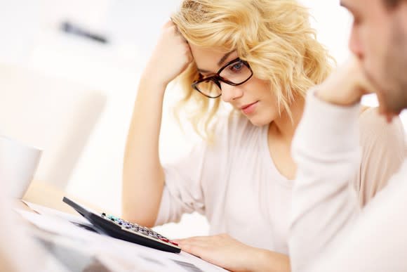 A young woman preparing her taxes with a calculator by her side.