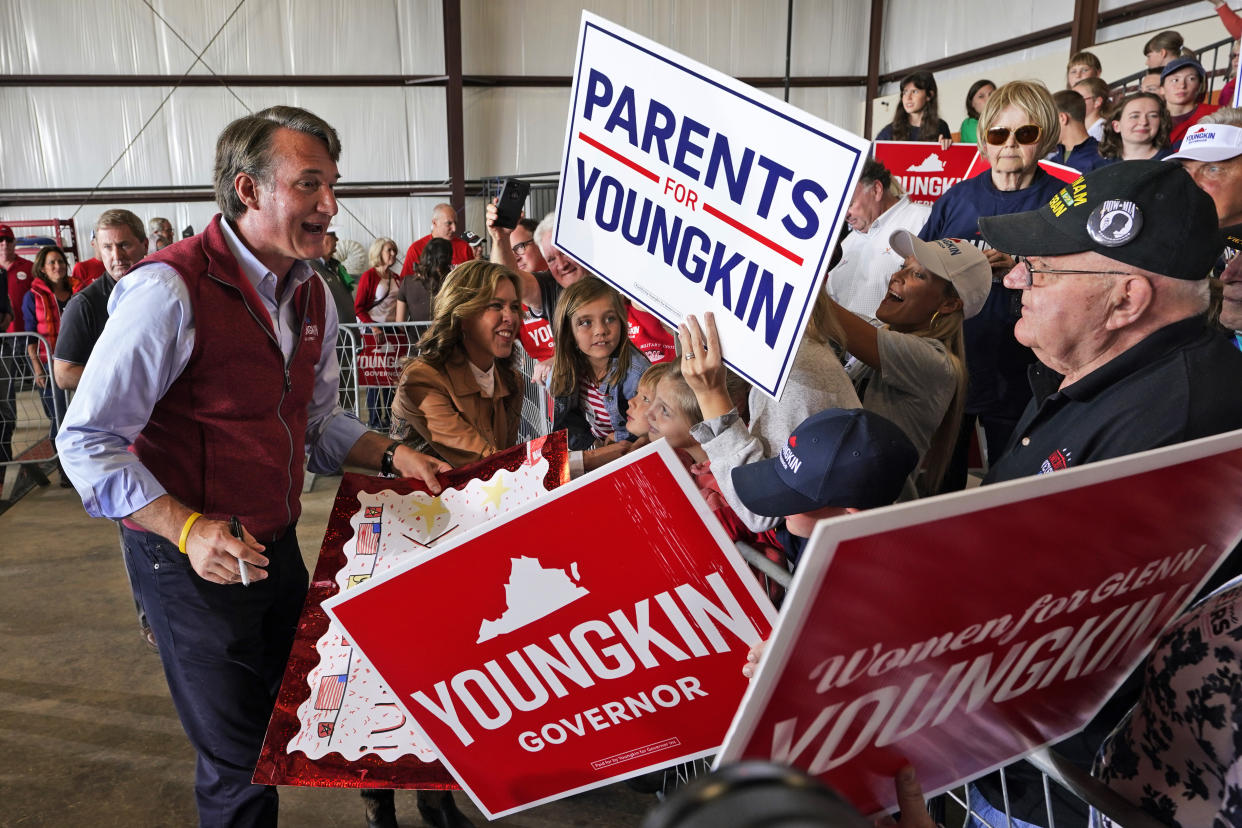 The Republican gubernatorial candidate Glenn Youngkin, left, and his wife, Suzanne, second from left, greet supporters during a rally in Chesterfield, Va., in November.  Placards are held by the audience saying 