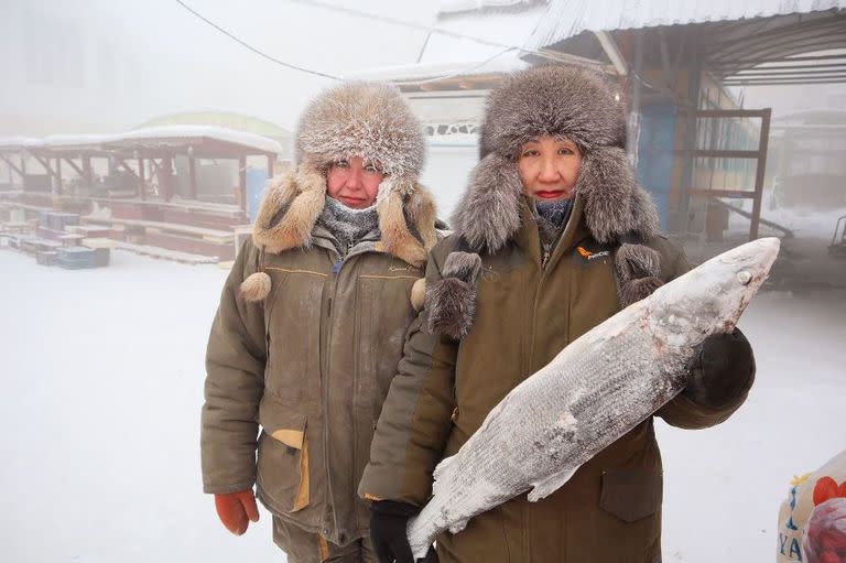 Las vendedoras de pescado Marina Krivolutskaya y Marianna Ugai posan para una foto en un mercado al aire libre en un día helado en Yakutsk, Rusia, el 15 de enero de 2023