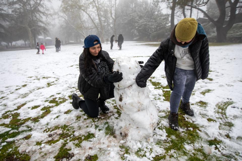 A parent and child build a snowman.