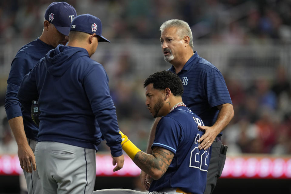 Tampa Bay Rays' Jose Siri (22) is attended to by trainers and manager Kevin Cash, left, after being hit by a pitch during the fifth inning of a baseball game against the Minnesota Twins, Monday, Sept. 11, 2023, in Minneapolis. (AP Photo/Abbie Parr)