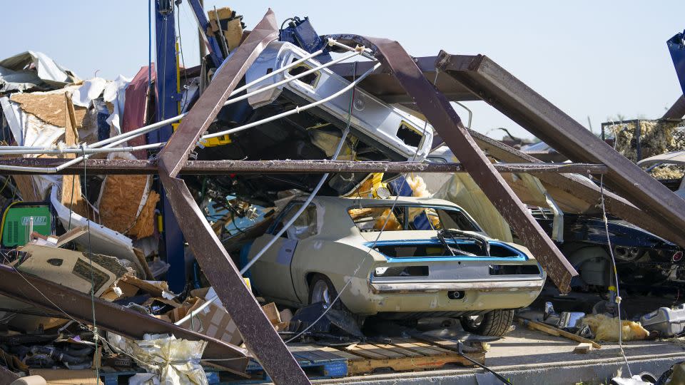 Vehicles in a body shop are seen amid debris the morning after a tornado rolled through in Valley View, Texas. - Julio Cortez/AP