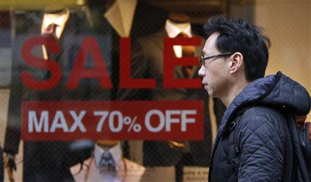 A man walks past a shop window with signs advertising a sale at a shopping district in Tokyo January 30, 2014. REUTERS/Yuya Shino