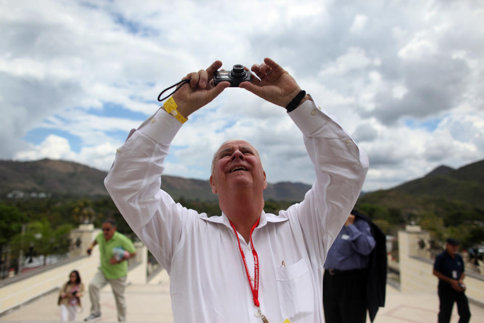 Cuban-American Nestor Machado, who left Cuba 52 years ago, takes pictures outside the Virgin of Charity of Cobre Catholic church in El Cobre near Santiago de Cuba, Cuba, Monday March 26, 2012. More than 300 Cuban-Americans and other pilgrims have arrived in Cuba for Pope Benedict XVI's visit on a trip led by Miami Archbishop Thomas Wenski. (AP Photo/Esteban Felix)