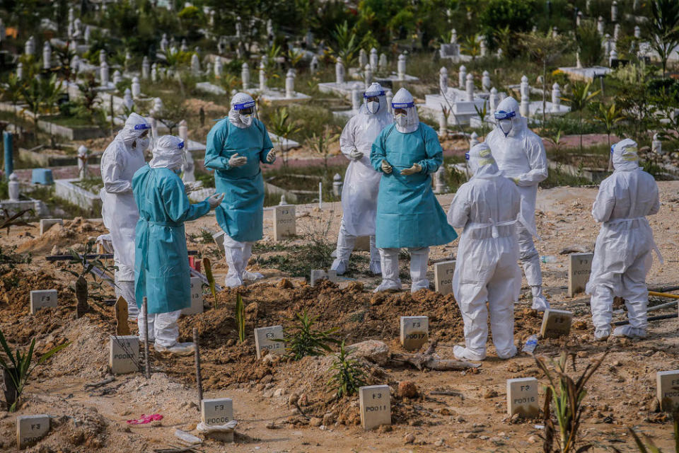 Workers wearing personal protective equipment recite a prayer after burying a victim who died from Covid-19 at the Muslim cemetery in Gombak June 8, 2021. ― Picture by Hari Anggara