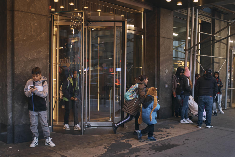 Migrant families leave for a walk to school in front of the Row Hotel that serves as migrant shelter on Tuesday, Dec. 12, 2023, in New York. It could be a cold, grim New Year for thousands of migrant families living in New York City’s emergency shelter system. With winter setting in, they are being told they need to clear out, with no guarantee they’ll be given a bed elsewhere. (AP Photo/Andres Kudacki)