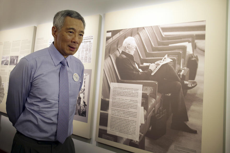 FILE - In this Wednesday, March 23, 2016 file photo, Prime Minister Lee Hsien Loong walks past an old photograph of his father, the late Lee Kuan Yew during a remembrance ceremony held at the old Parliament House to mark the first death anniversary of Singapore's founding Prime Minister Lee Kuan Yew, in Singapore. The prime minister's father ruled the country for three decades and turned it into an affluent city-state. (AP Photo/Wong Maye-E, File)
