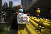 Pro-democracy activists holding a copy of Apple Daily newspaper and banner protest outside a court in Hong Kong, Saturday, June 19, 2021, to demand to release political prisoners. The top editor of the Hong Kong's pro-democracy newspaper and the head of its parent company were brought to a courthouse Saturday for their first hearing since their arrest under the city's national security law.(AP Photo/Kin Cheung)