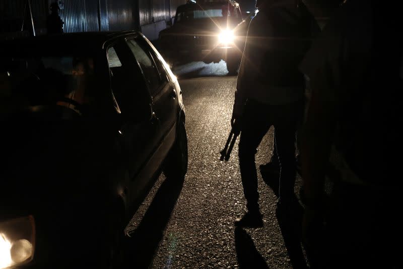 Members of the Special Action Force of the Venezuelan National Police (FAES) stand between passing cars during a night patrol, in Barquisimeto
