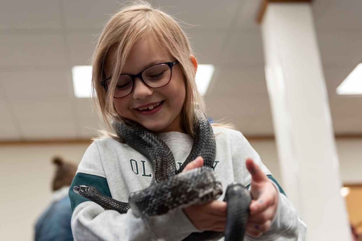 Gracelynn Warner holds a black rat snake around her neck during the Earth Plus Expo, presented by Earth Week Plus, at the Cheboygan Area Public Library on Saturday, April 20, 2024.