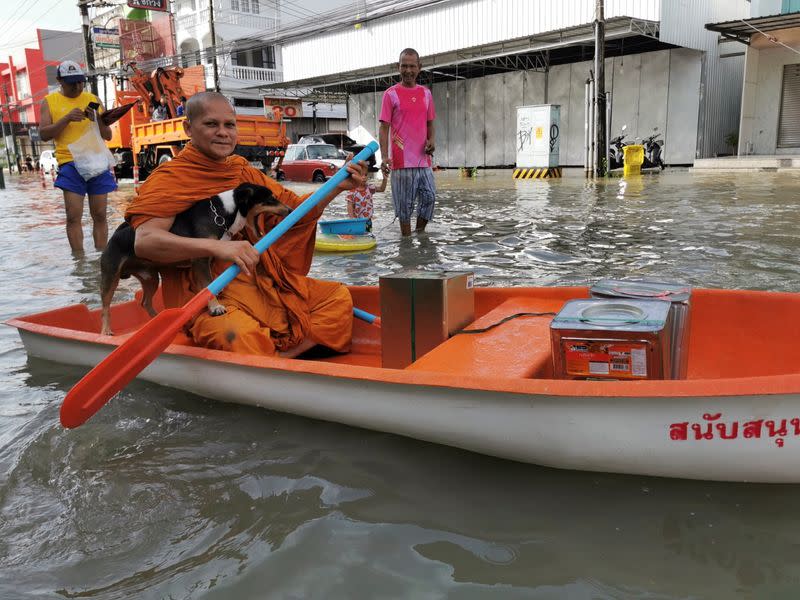 Buddhist monk paddles a boat down a flooded street in Nakon Si Thammarat province