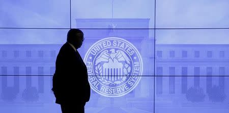 A security guard walks in front of an image of the Federal Reserve in Washington, DC, U.S., March 16, 2016. REUTERS/Kevin Lamarque/File Photo