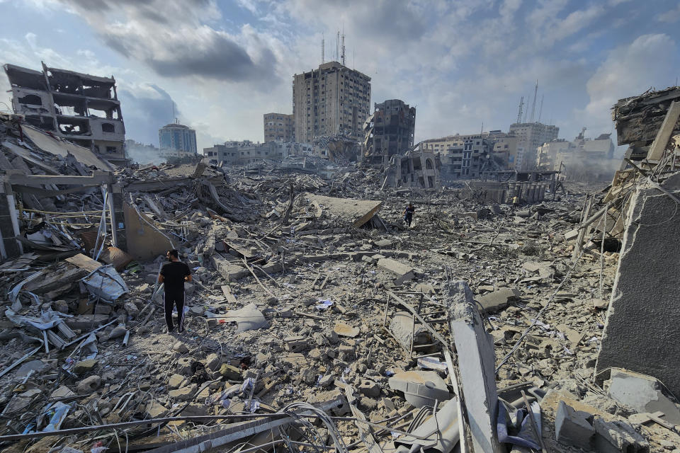 Palestinians walk through the rubble of buildings destroyed by Israeli airstrikes in Gaza City on Tuesday, Oct. 10, 2023. (AP Photo/Hassan Eslaiah)