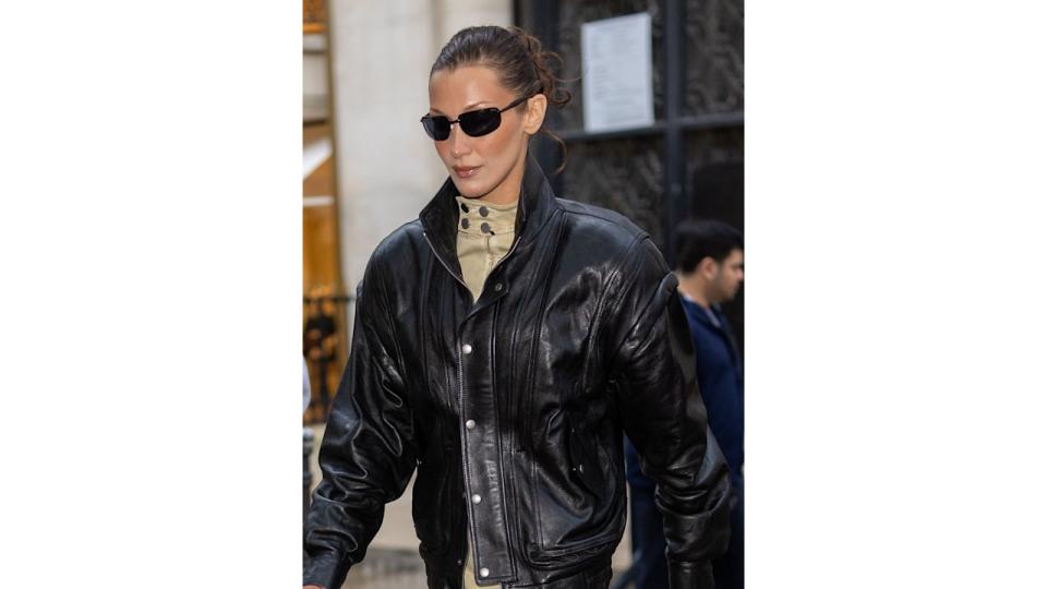 Bella Hadid is seen on September 23, 2024 in Paris, France wearing a set of black sunglasses, a leather jacket and beige dress