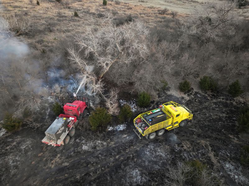 A drone view shows firefighters spraying trees with water in Roberts County