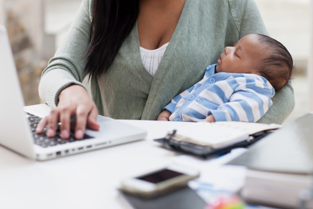 Mother using laptop computer as she cares for baby