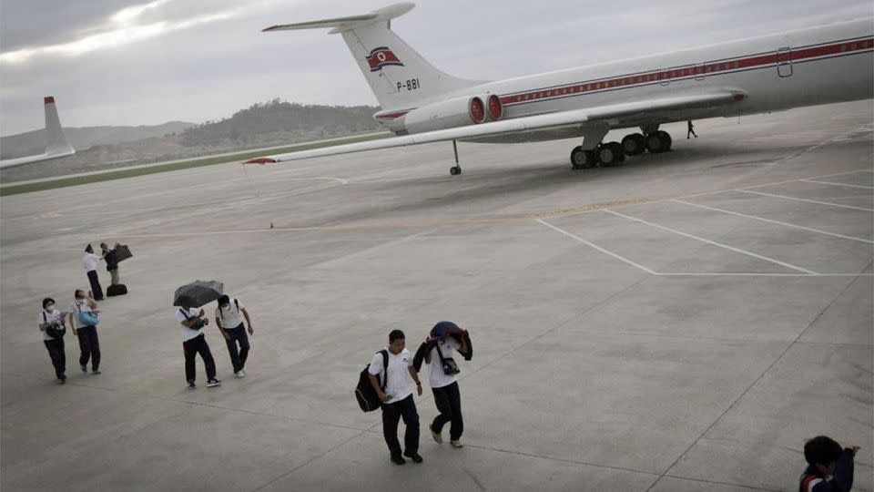 Passengers walk past an Air Koryo plane on the tarmac of the Pyongyang International Airport. Photo: AP Photo/Wong Maye-E