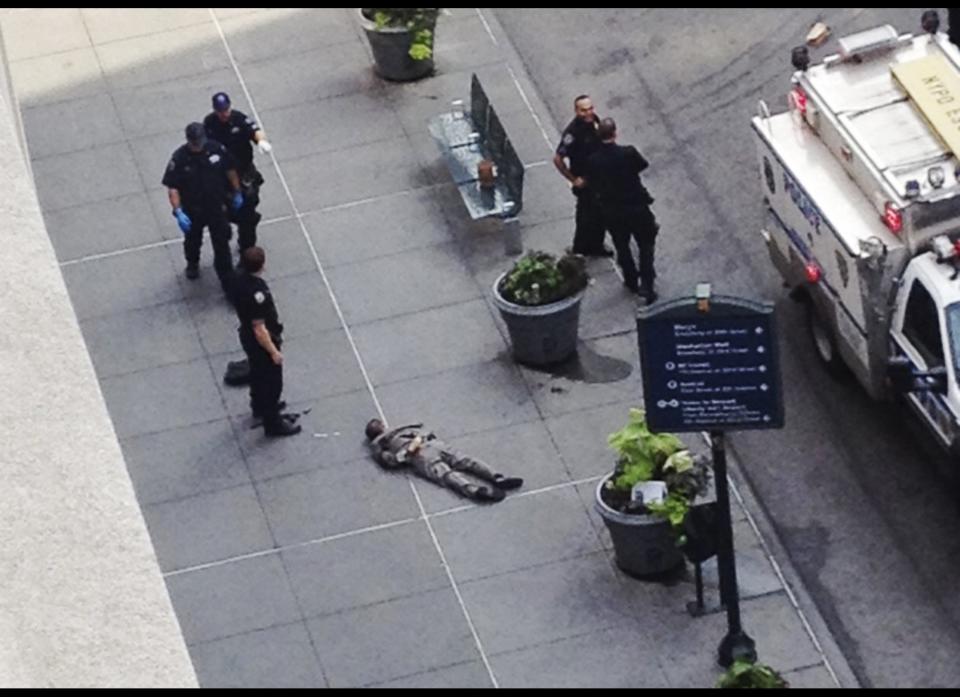 New York City police approach the lifeless body of Jeffrey Johnson lying on a sidewalk near the Empire State Building in New York following a shooting Friday, Aug. 24, 2012. Police say 58-year-old Johnson, who was laid off from a nearby shop in 2011, shot a former colleague to death near the iconic skyscraper, then randomly opened fire on people nearby before firing on police. New York City Mayor Michael Bloomberg said some of the victims may have been hit by police bullets as police and the gunman exchanged fire. (AP Photo/Guillermo Ratzlaff)