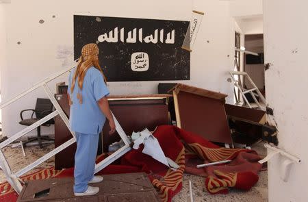 A Libyan man checks a building used by the Islamic State fighters after it was captured by Libyan forces allied with the U.N.-backed government, in Sirte, Libya. REUTERS/Hani Amara