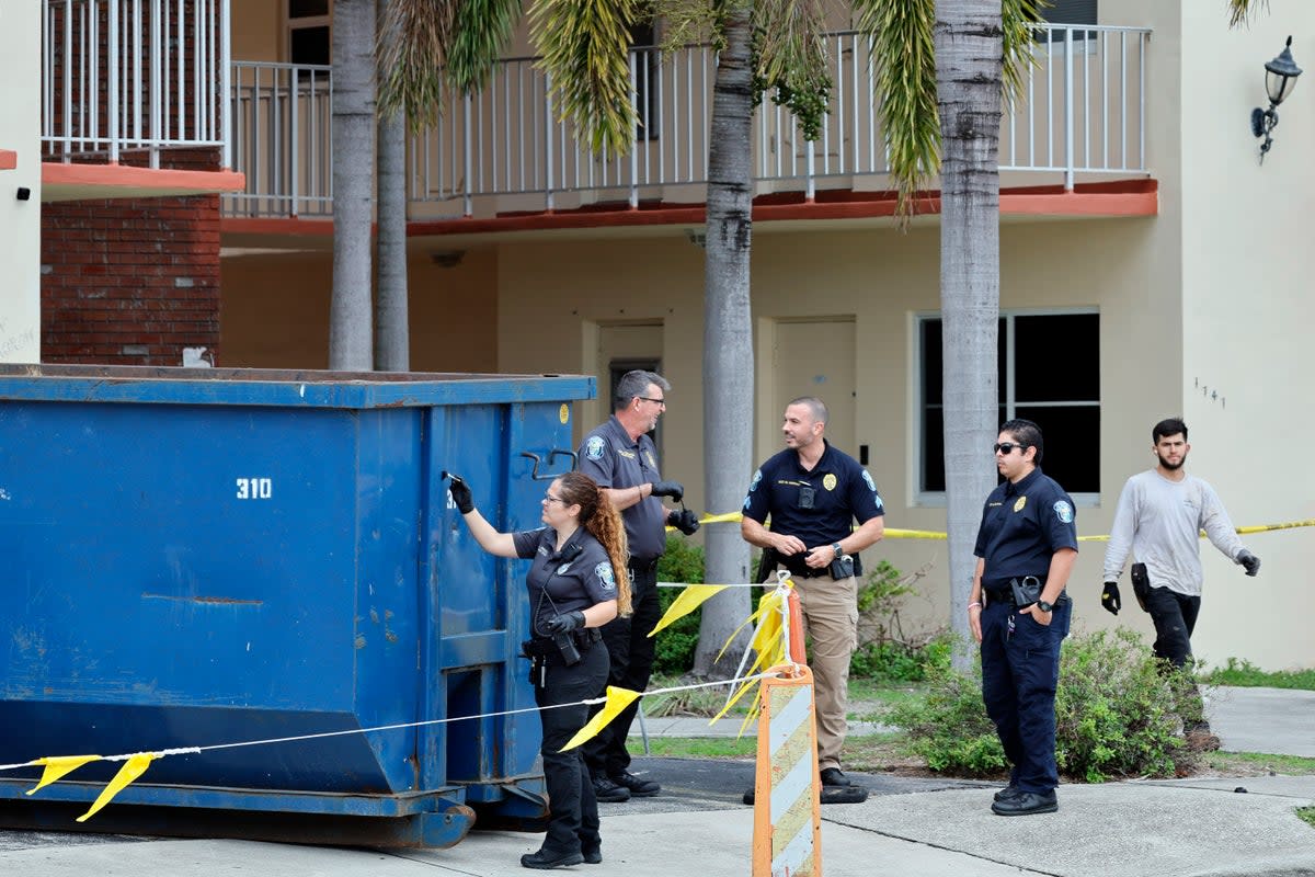 A crime scene investigator dusts for fingerprints at a large trash bin outside of an apartment complex in Hollywood, Florida, where construction workers found a dead baby on 8 January (AP)