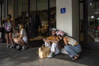 Israelis take cover as a siren warns of incoming rockets fired from the Gaza Strip, in Tel Aviv, Israel, Friday, Oct. 27, 2023. (AP Photo/Oded Balilty)