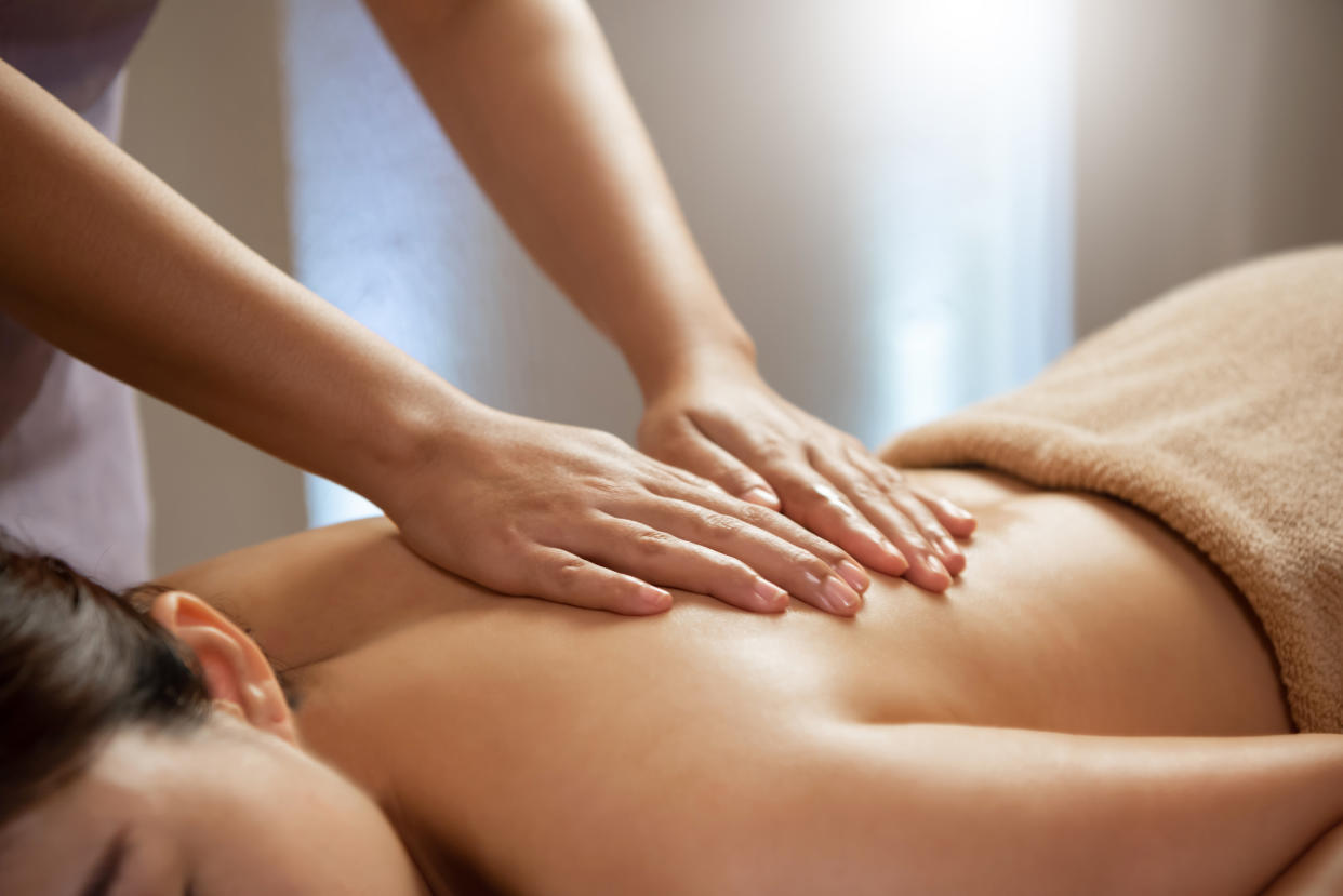 Massage therapist working on Asian female body in the spa salon.
