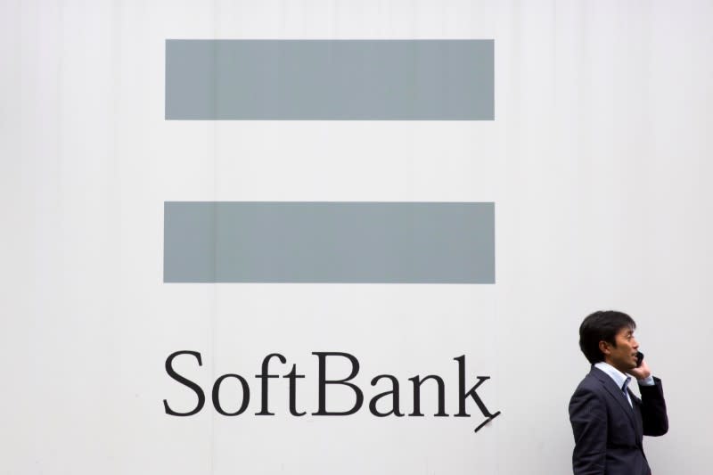 A man talks on the phone as he stand in front of an advertising poster of the SoftBank telecommunications company in Tokyo October 16, 2015. REUTERS/Thomas Peter