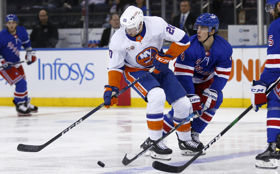 New York Islanders forward Hudson Fasching, left, and New York Rangers defenseman Braden Schneider vie for the puck during the second period of an NHL hockey game Thursday, Dec. 22, 2022, in New York. (AP Photo/John Munson)