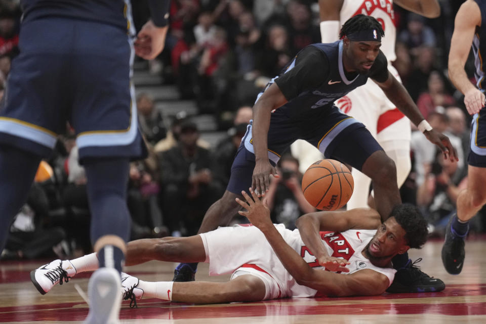 Toronto Raptors forward Thaddeus Young (21) and Memphis Grizzlies guard Vince Williams Jr. (5) battle for the ball during the second half of an NBA basketball game in Toronto, Monday, Jan. 22, 2024. (Nathan Denette/The Canadian Press via AP)