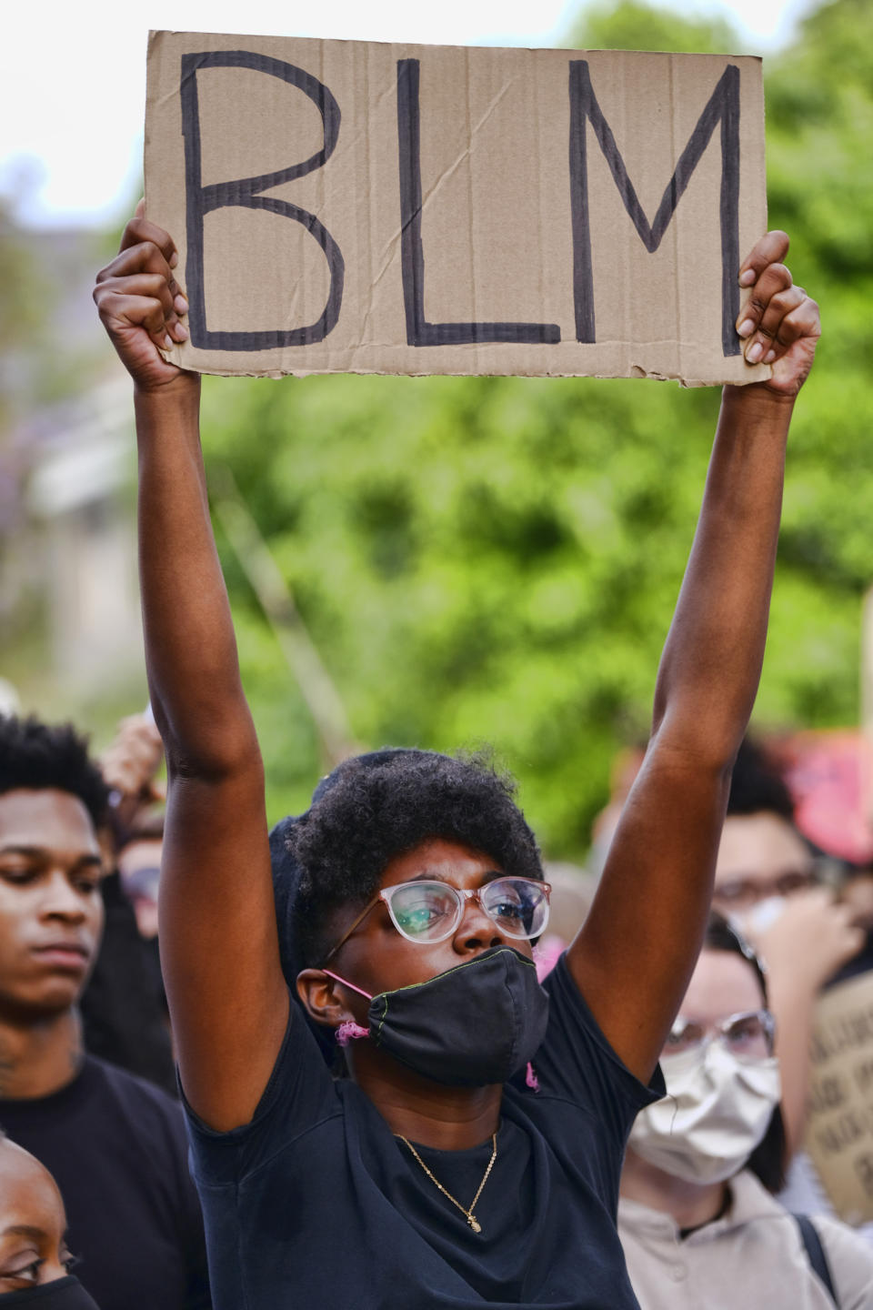 Pictured is a Black Lives Matter protester holding up a sign with the letters BLM. 